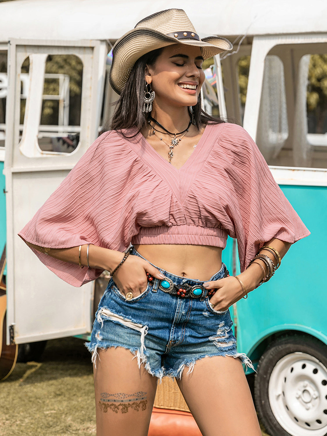 Boho crop top with textured V-neck and ruched design, paired with distressed shorts.