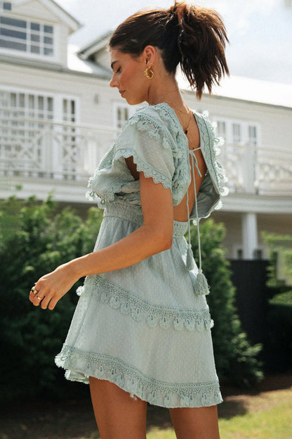 Lace detail plunge short sleeve mini dress in light blue cotton, featuring tied back and intricate lace accents.