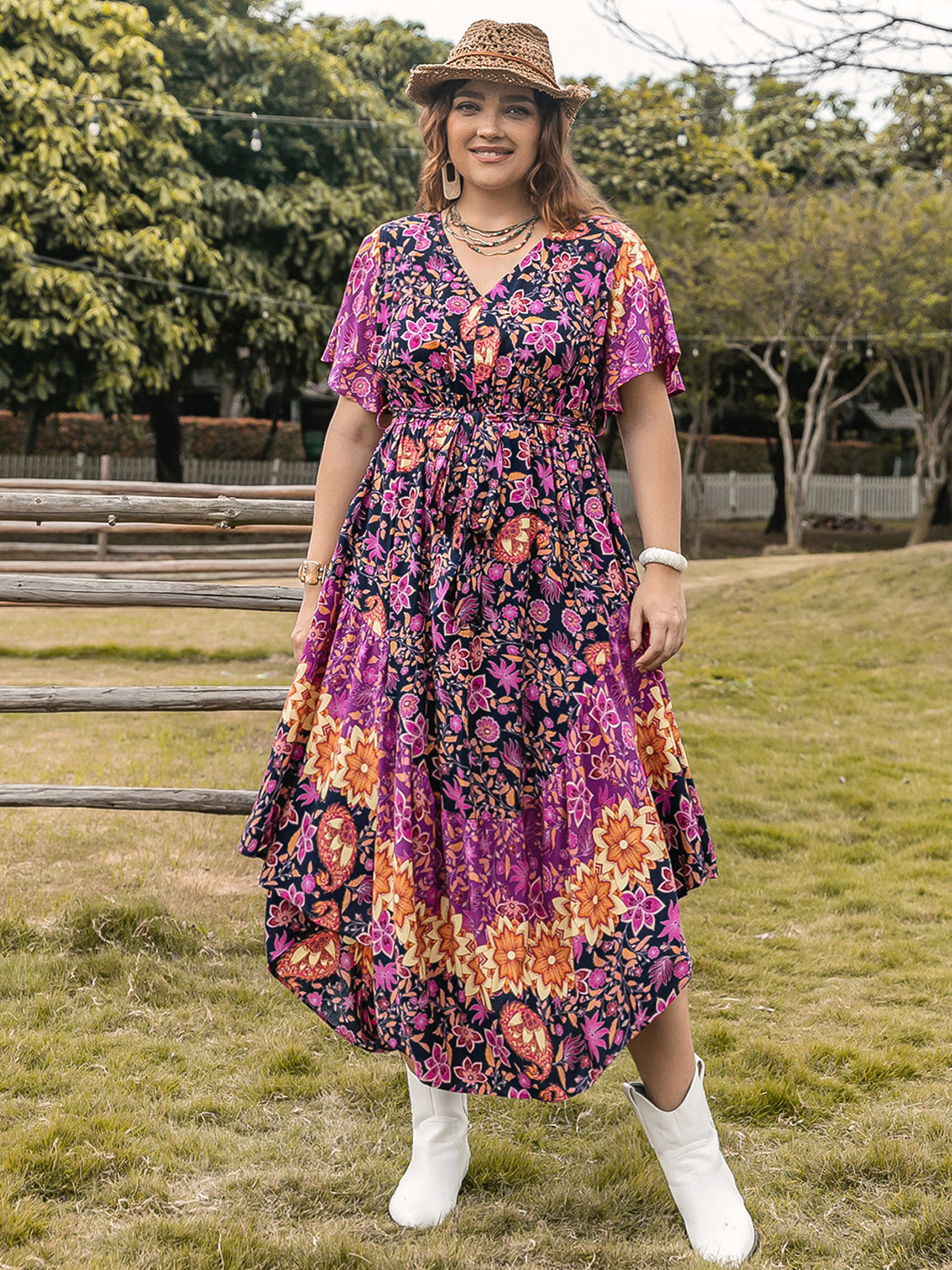 Plus size printed V-neck flutter sleeve midi dress in vibrant colors, worn outdoors.