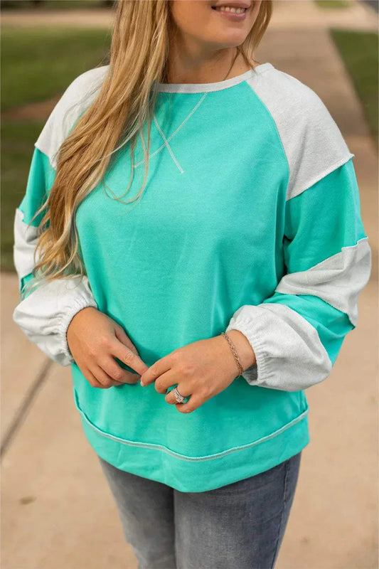 Plus size exposed seam color block long sleeve sweatshirt in green and white.