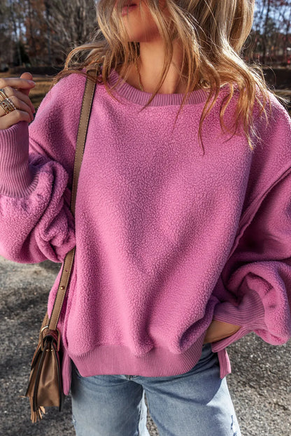 Slit round neck long sleeve sweatshirt in pink with exposed seam and high-low design.