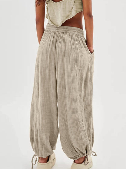 Textured tied pants with pockets, made of polyester and spandex, shown in a light color.