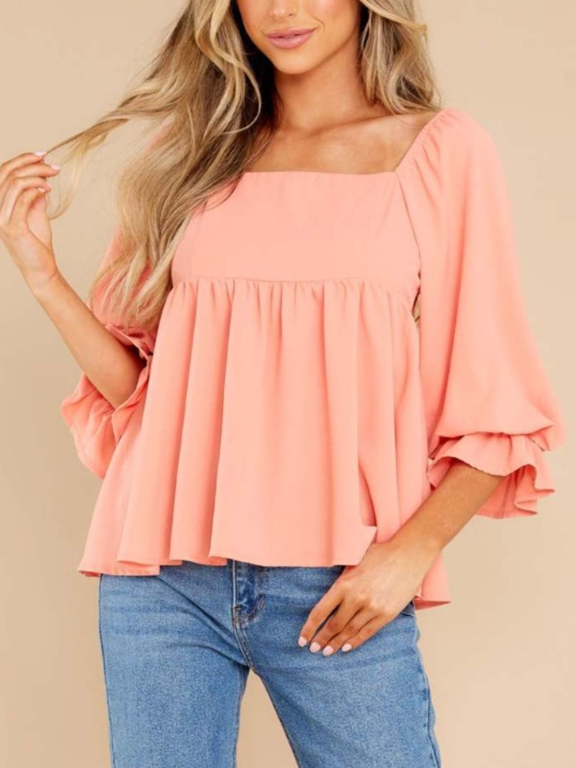 Smocked square neck flounce sleeve blouse in coral pink, worn by a model.