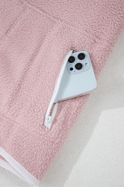 Pink fleece jacket with pocket detail, featuring a zipper closure and holding a smartphone.