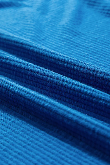 Close-up of blue fabric texture for an exposed seam notched long sleeve blouse.