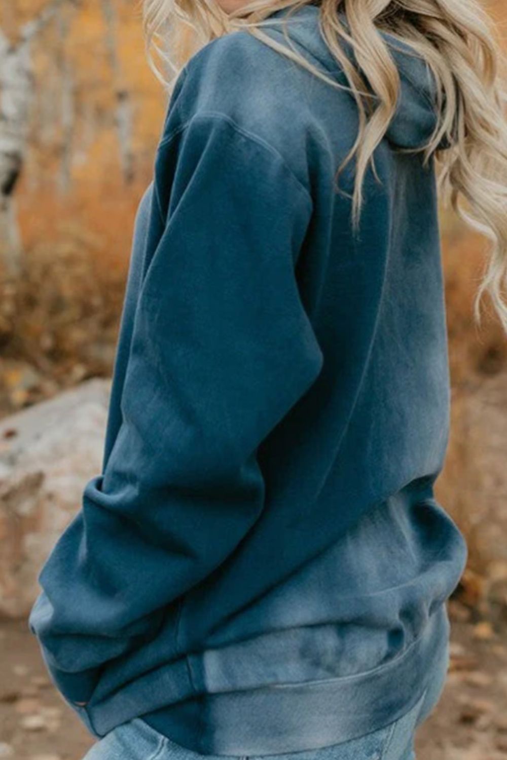 Drawstring pocketed dropped shoulder hoodie in blue worn outdoors.