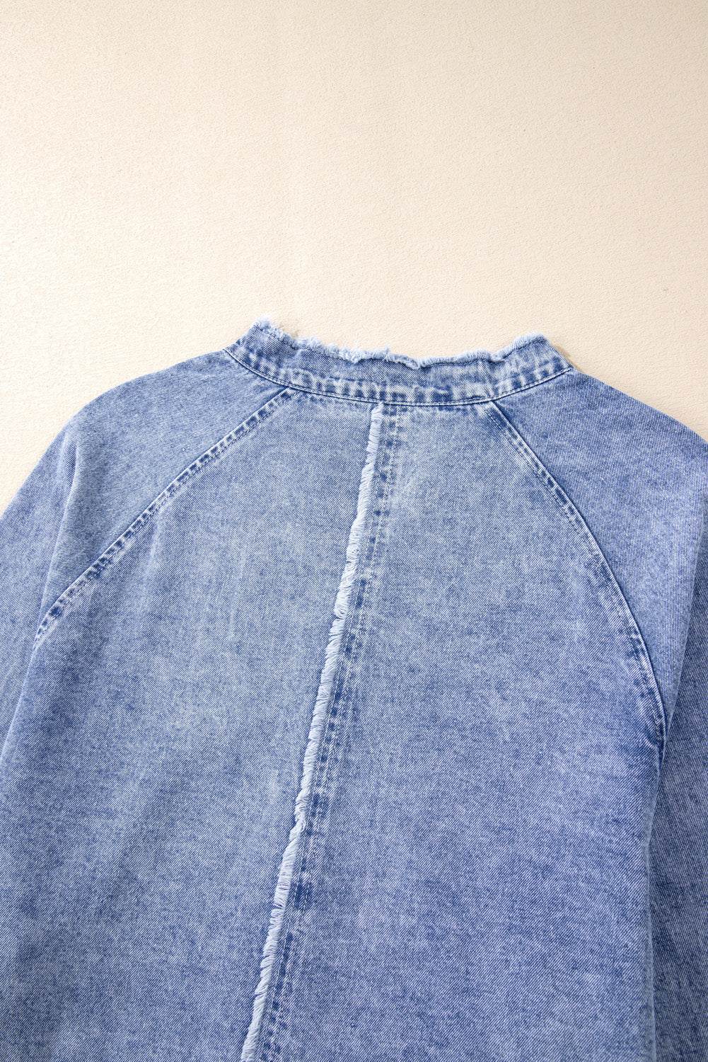 Raw hem button down long sleeve denim dress with a back view.