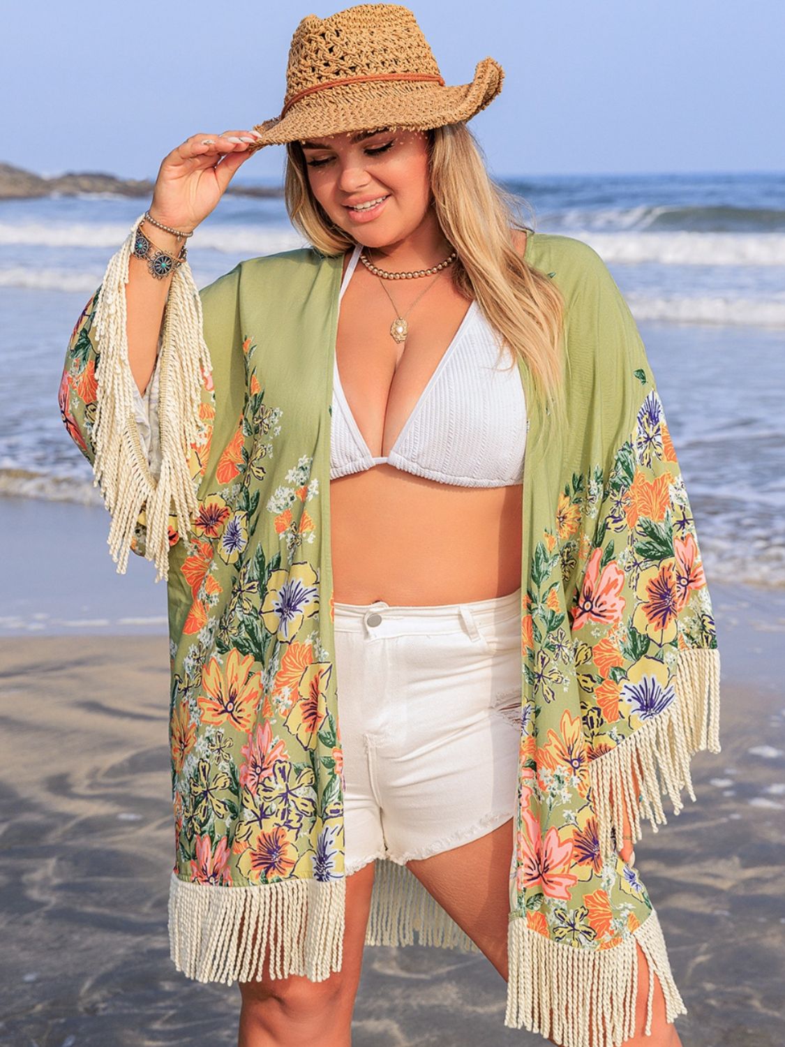 Plus size fringe open front cover-up on woman at beach.