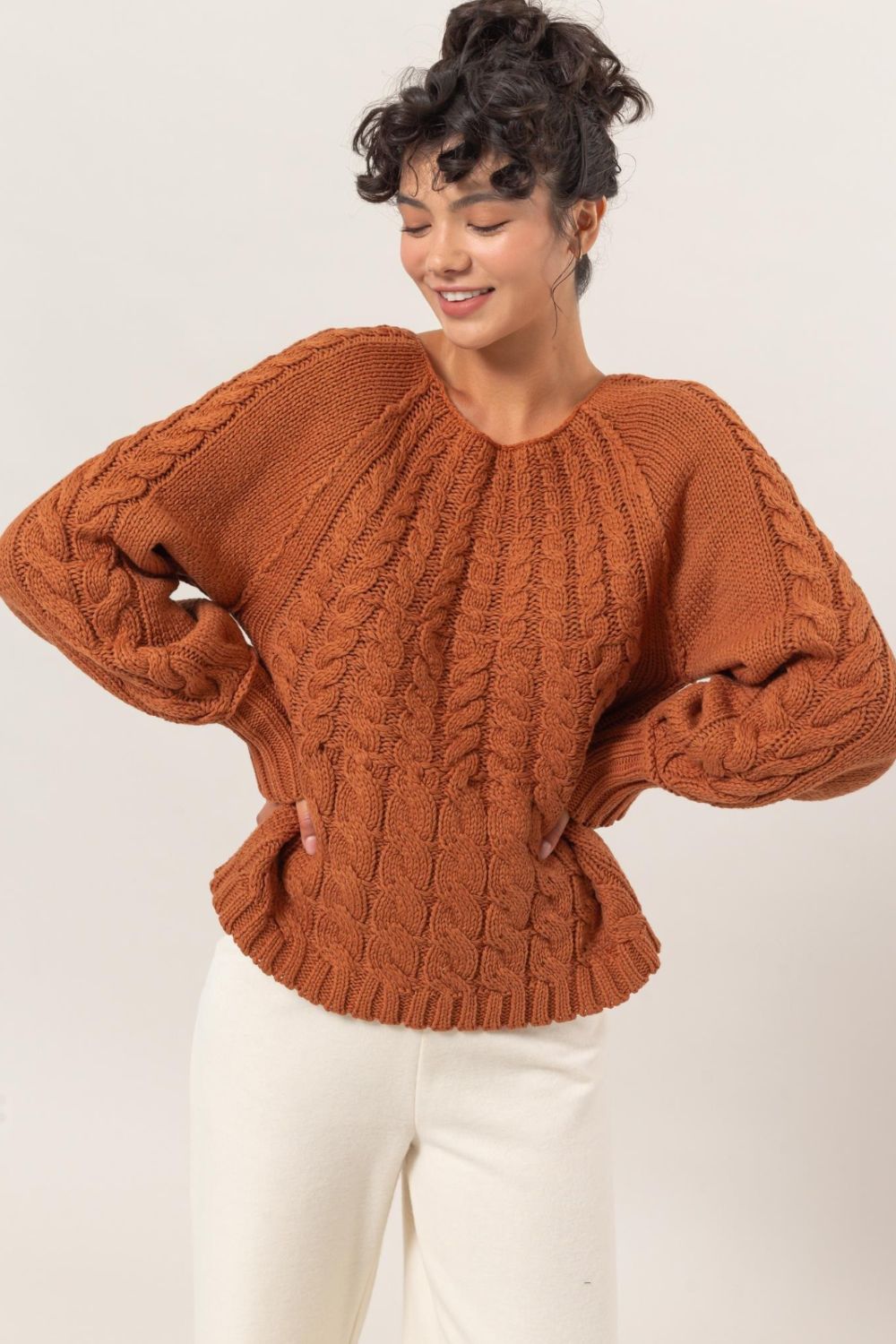 Cable knit round neck raglan sleeve sweater in brown.