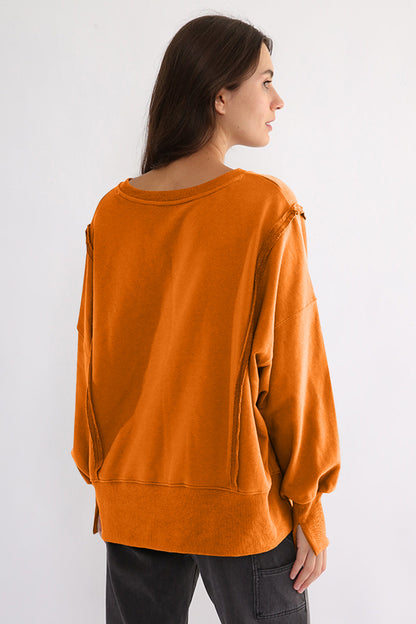 Exposed seam high-low sweatshirt with long sleeves in orange.